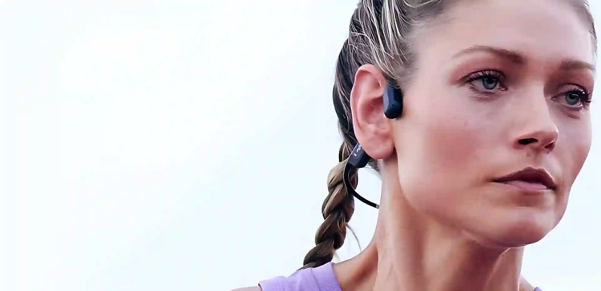 Coureuse portant un casque à conduction osseuse bleu nuit, l'oreille entièrement dégagée